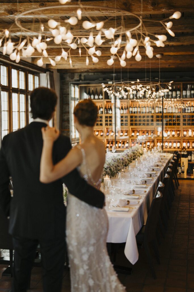Brautpaar betrachtet die Hochzeitstafel im Weinkeller