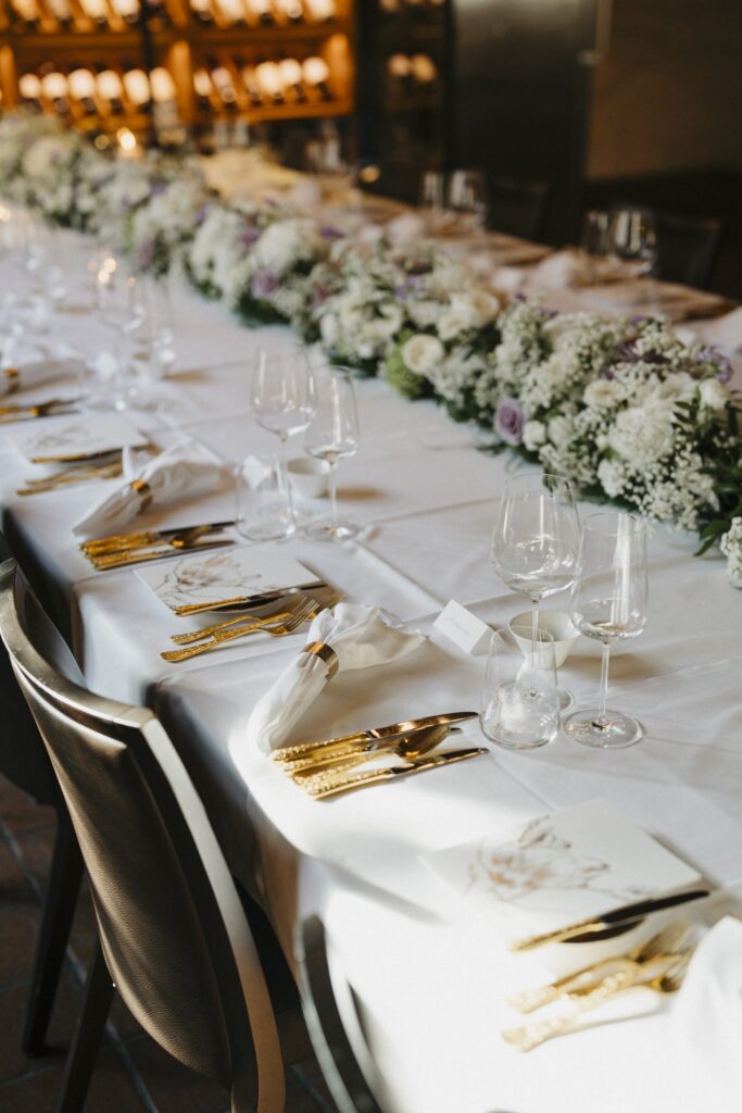 Hochzeitstafel mit goldenem Besteck und Blumengirlande