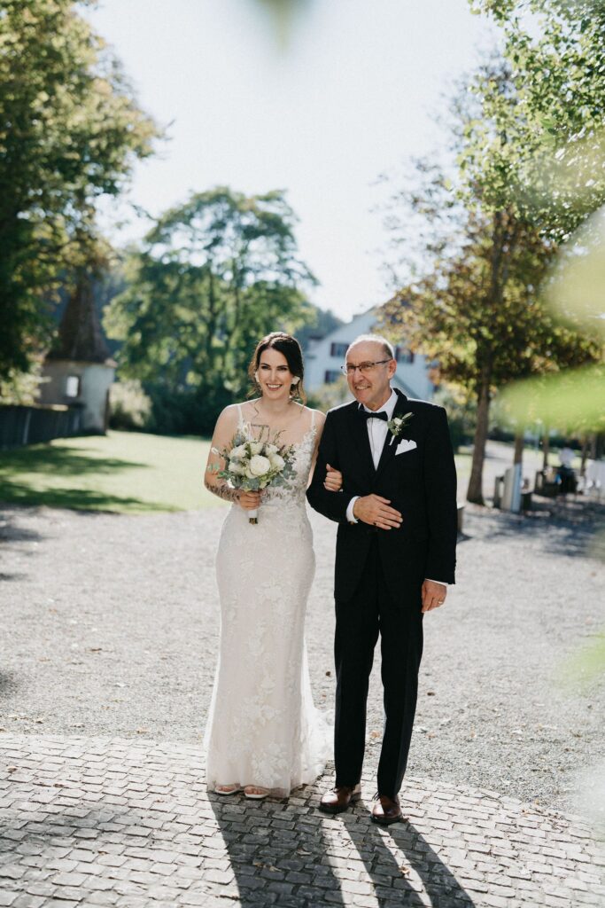 Braut mit ihrem Vater auf dem Weg zur Kirche